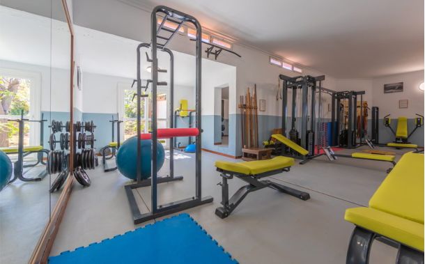Gimnasio del Hotel Hurricane en Tarifa, equipado con máquinas de musculación, pesas y material fitness, con luz natural y vistas al jardín.